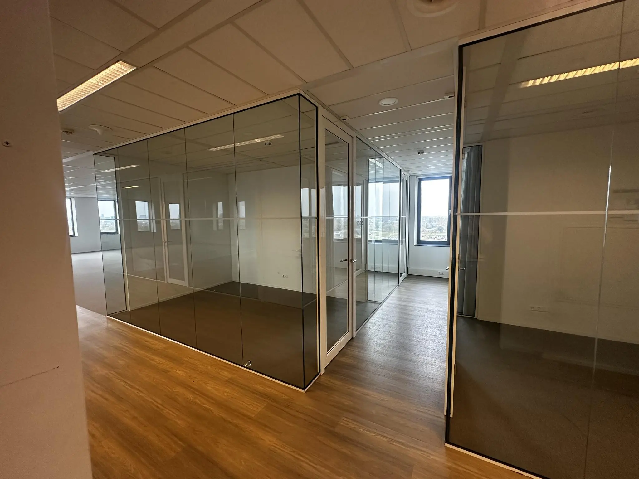 Modern kantoorinterieur aan de Laan van Zuid Hoorn met glazen wanden en houten vloer.